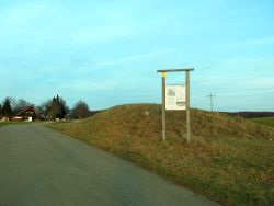 eine Tafel informiert über Tor F. Das Tor am Heidengraben ist der Zugang zur Elsachstadt von der Hülbener Halbinsel aus. Im Hintergrund sieht man die Gaststätte Burrenhof.