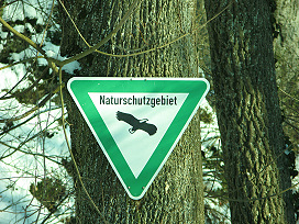 Foto: An einem Baumstamm ist das Schild “Naturschutzgebiet” befestigt.